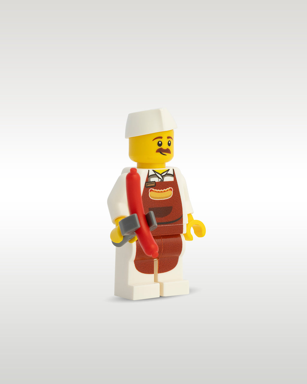 Side profile of the custom toy brick vendor minifigure holding a reddish-brown micro-scale hot dog sausage accessory