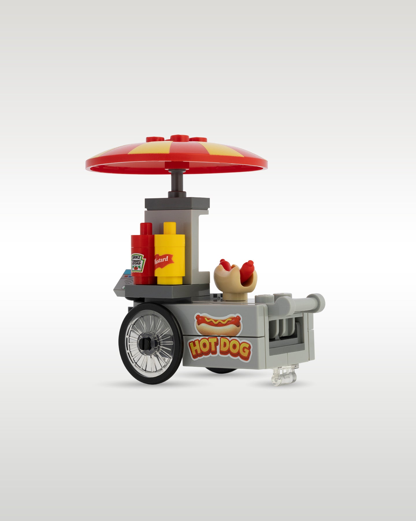 angled view of the custom brick hot dog cart model, showing the realistic ketchup and mustard dispenser bottles next to a hot dog bun on the prep counter