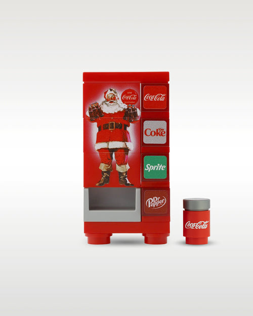 Custom brick-built Christmas Coca-Cola vending machine MOC set by Trader Bricks, featuring a classic red holiday Santa Claus graphic panel and a matching miniature soda can accessory