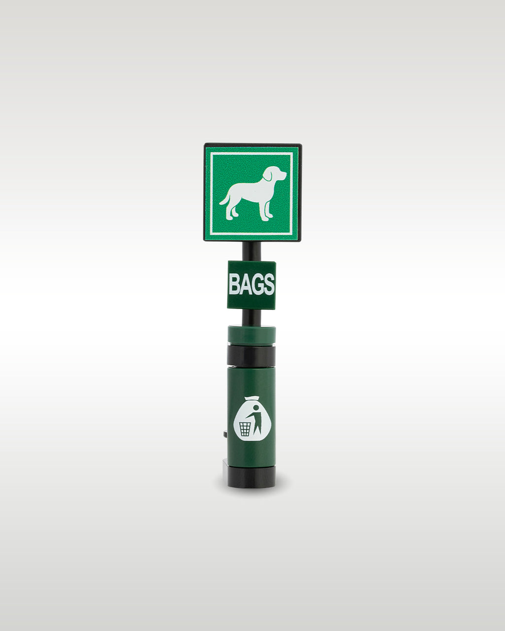 Custom brick-built pet clean up station model by Trader Bricks, featuring a green square sign with a custom printed white dog graphic, a 'BAGS' dispenser tile, and a dark green trash bin