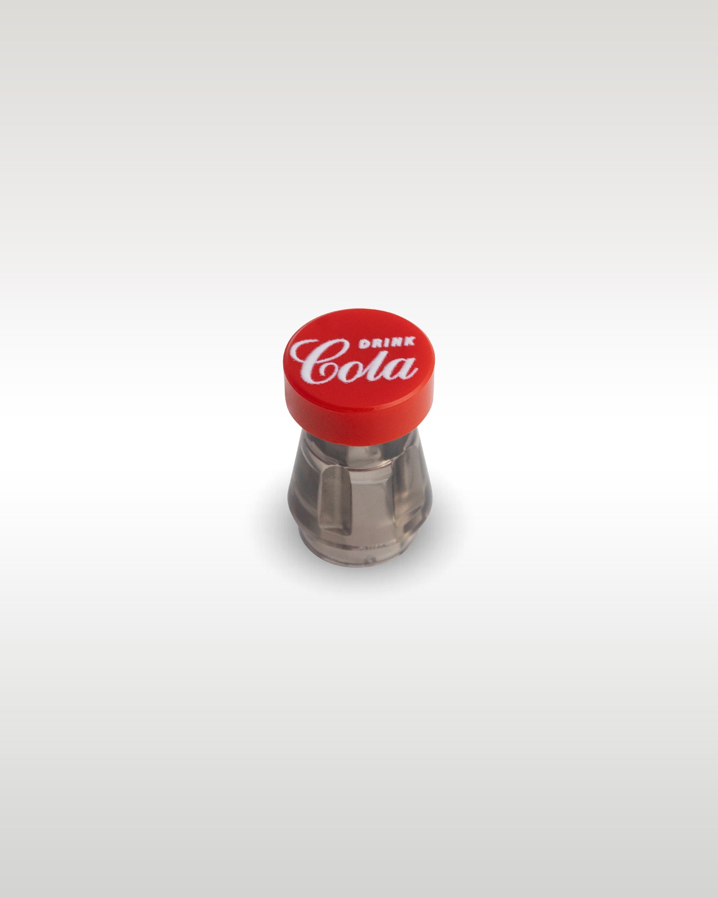 Close-up view of the custom miniature cola soda bottle accessory by Trader Bricks, featuring a clear cone element and a red round cap custom printed with an 'Enjoy Cola' logo